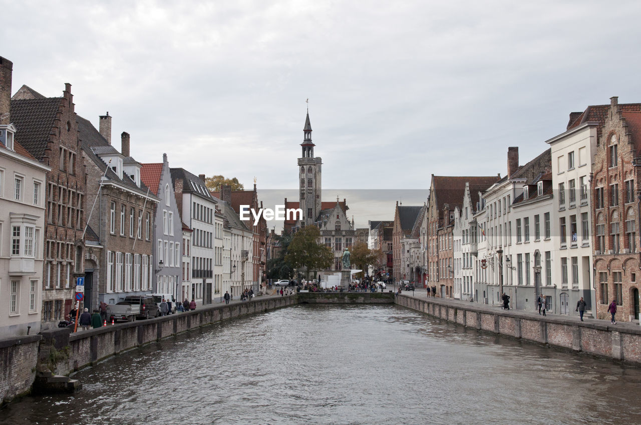 Canal amidst buildings in city against sky