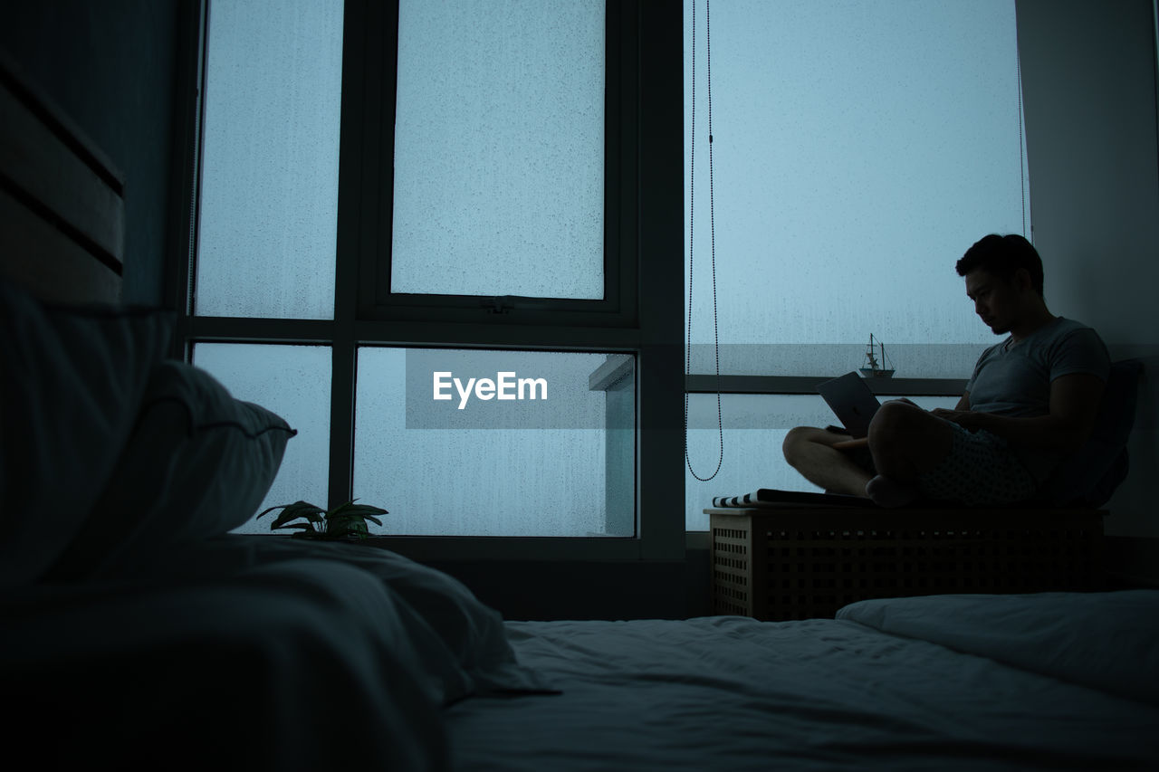 Man is sitting relax at the balcony in his room in the evening.