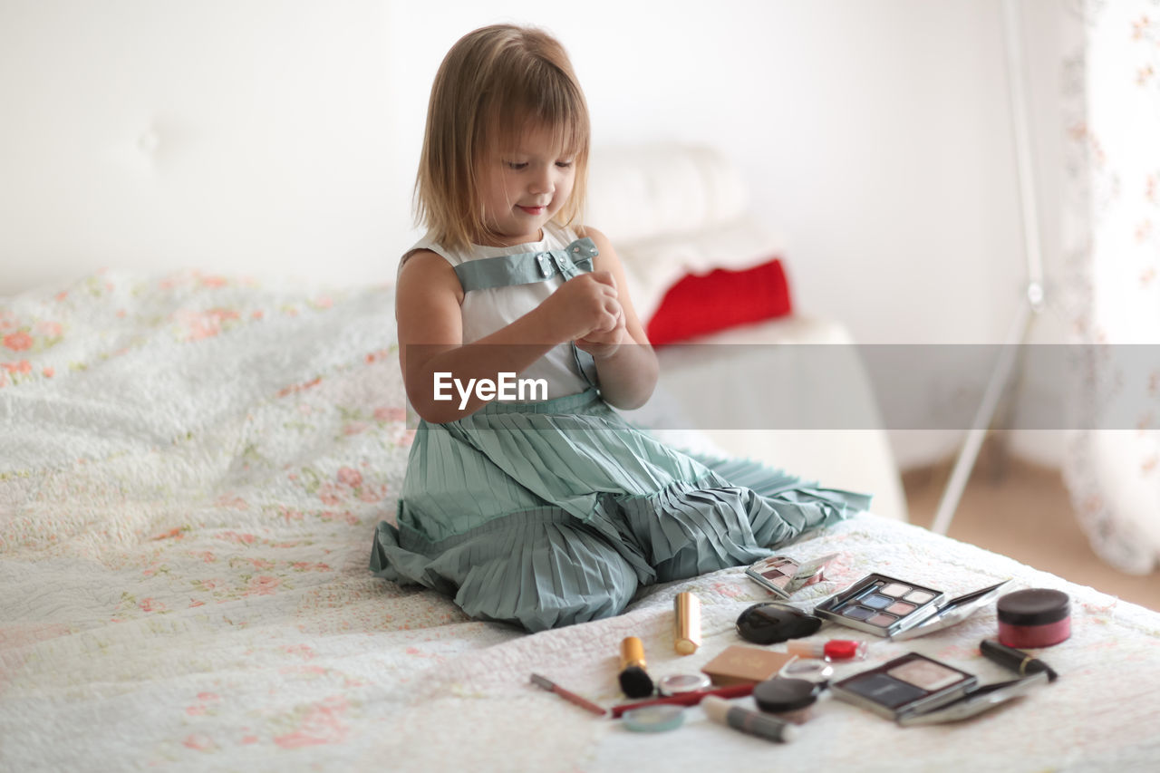 Kid girl in my mother's bedroom took out mother's make-up and lipstick, the concept of a  childhood 