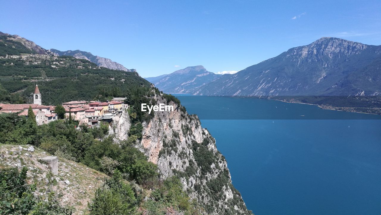 Scenic view of townscape by mountains against clear blue sky