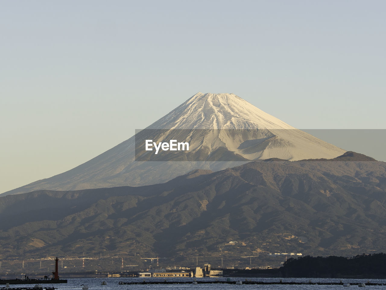 mountain, volcano, stratovolcano, water, sky, beauty in nature, scenics - nature, nature, travel destinations, no people, land, horizon, landscape, snow, travel, cinder cone, environment, sea, outdoors, day, non-urban scene, snowcapped mountain, volcanic landscape, tranquility, tourism, geology, cold temperature, tranquil scene, winter, clear sky, transportation, mountain peak