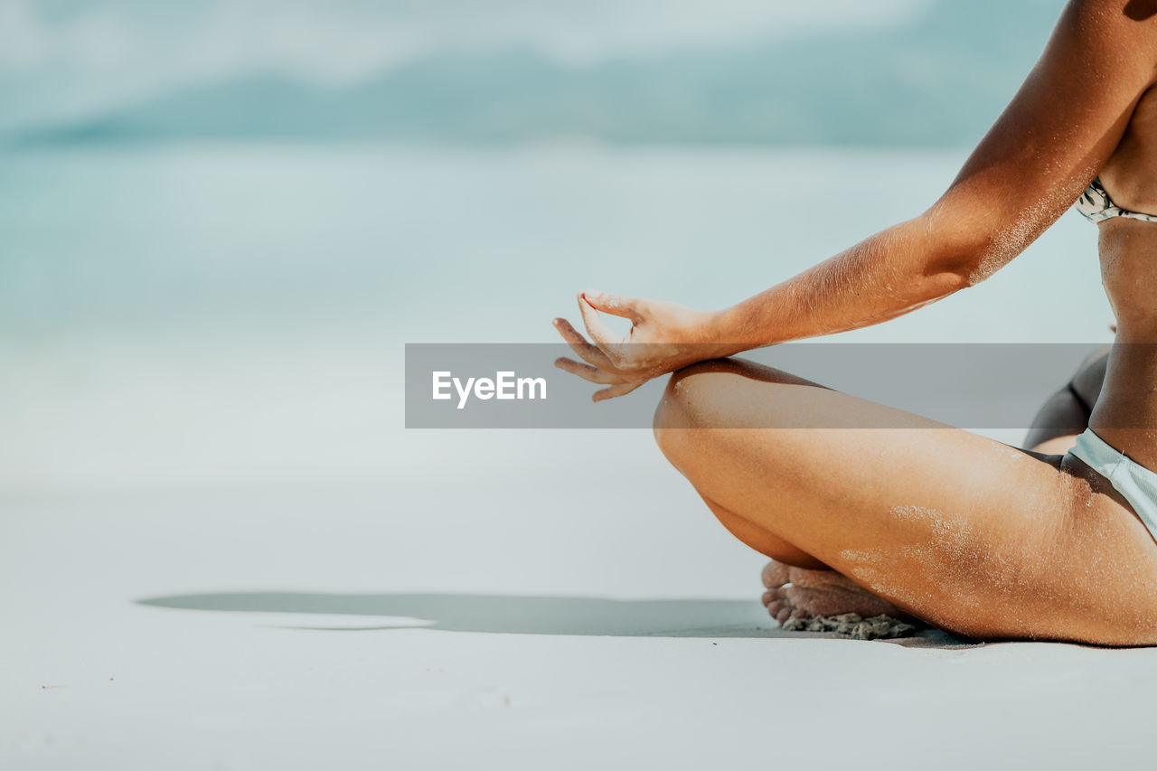 Low section of woman exercising at beach