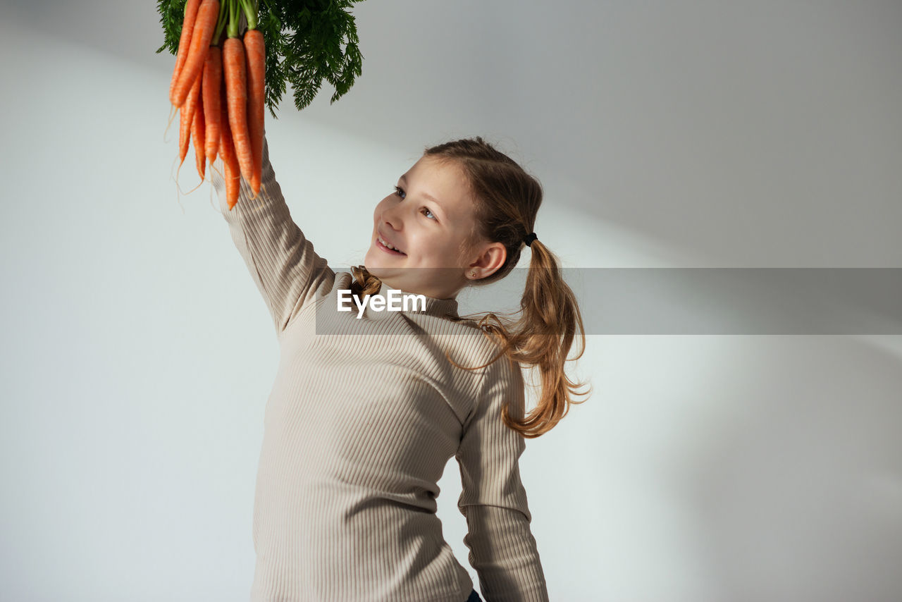 portrait of young woman with arms crossed standing against wall