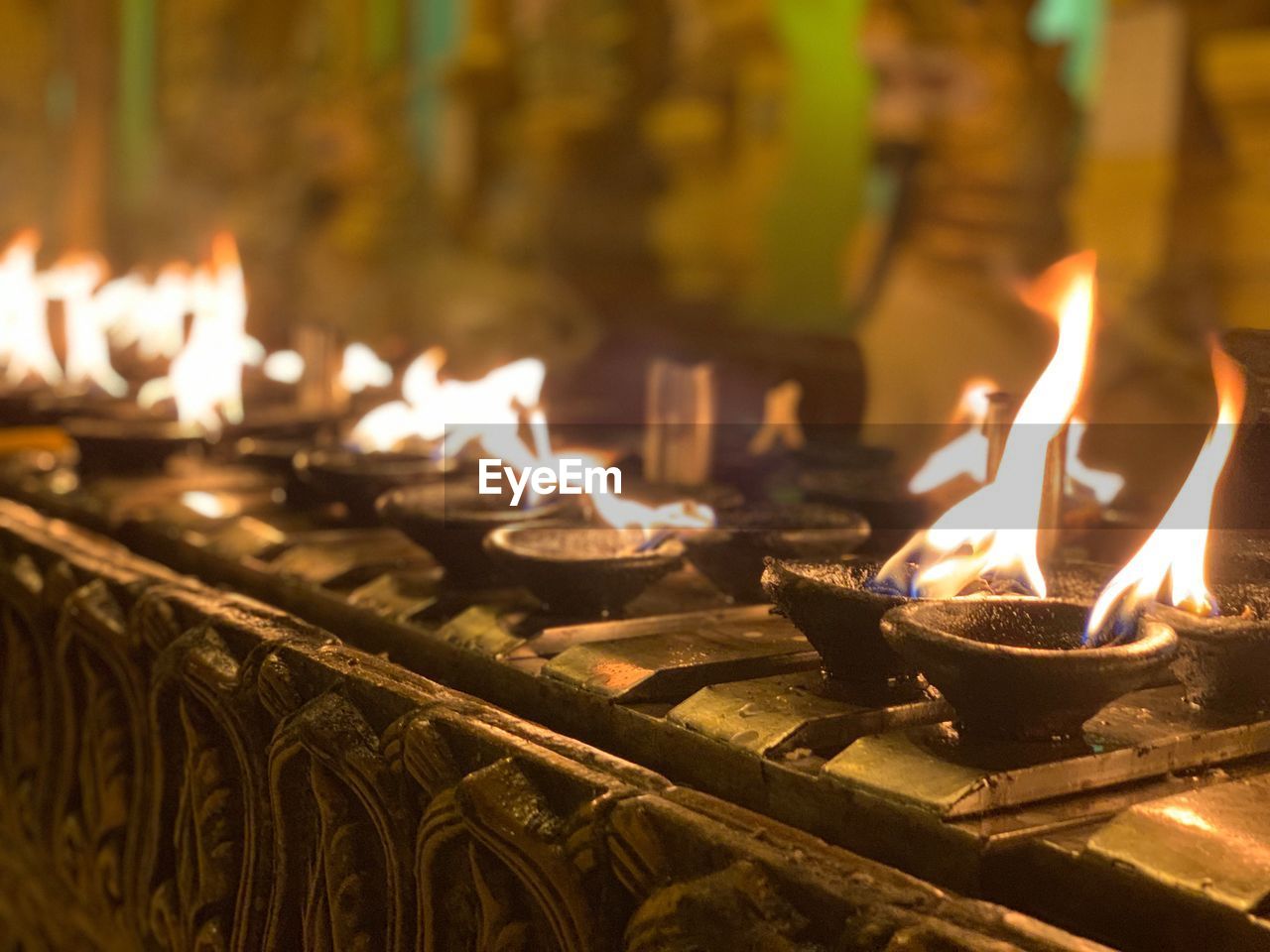Close-up of burning diyas at temple