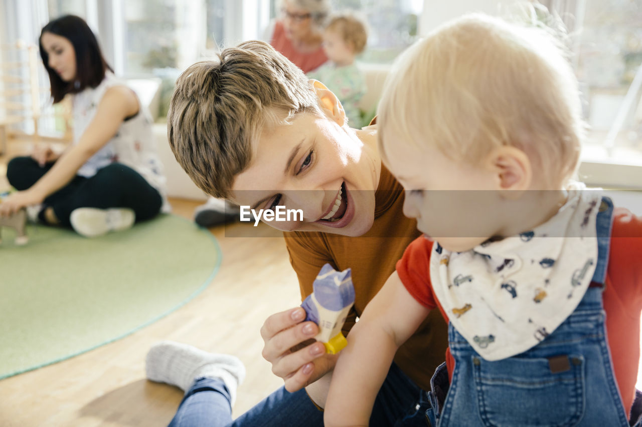 Pre-school teacher playing with toddler in kindergarten