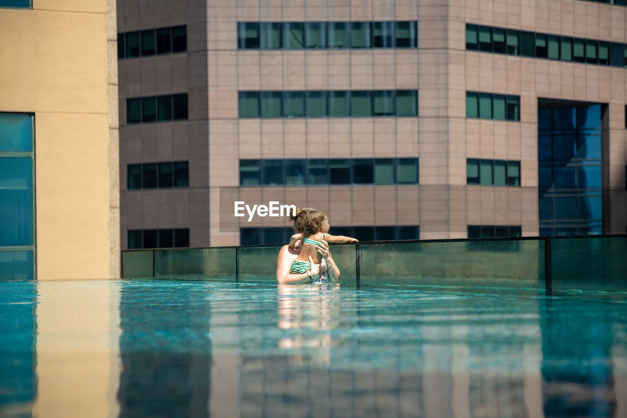 Full length of woman on swimming pool against building