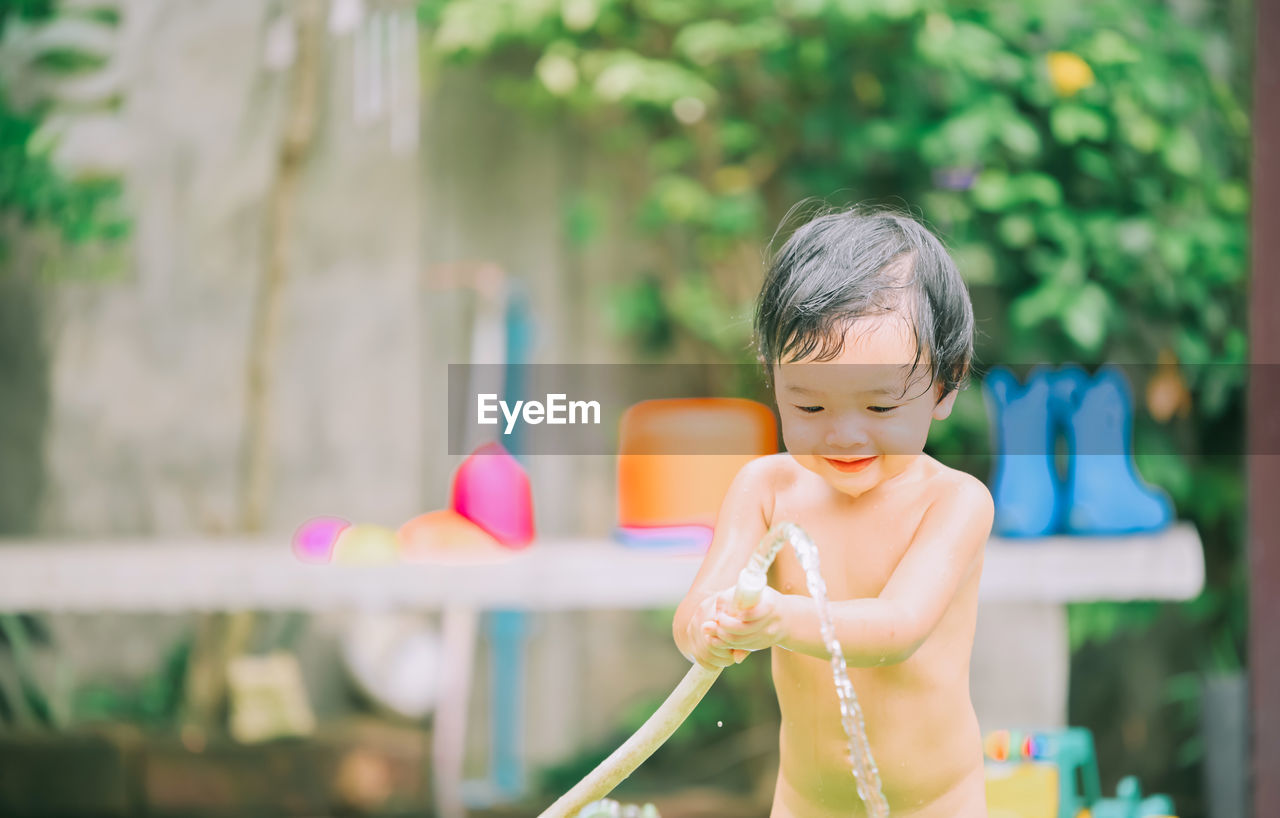 Cute girl playing with water pipe outdoors