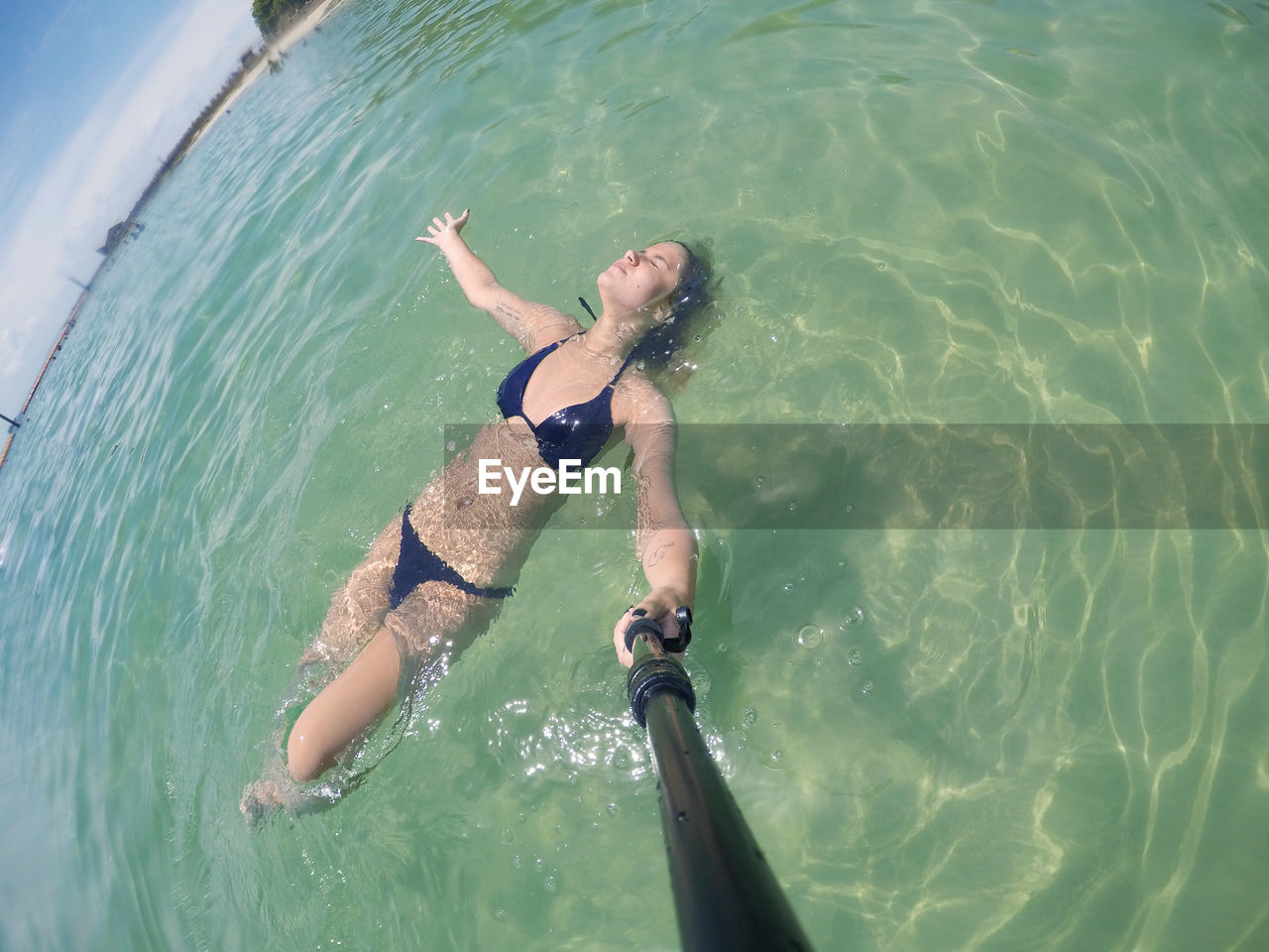 High angle view of young woman wearing bikini swimming in sea