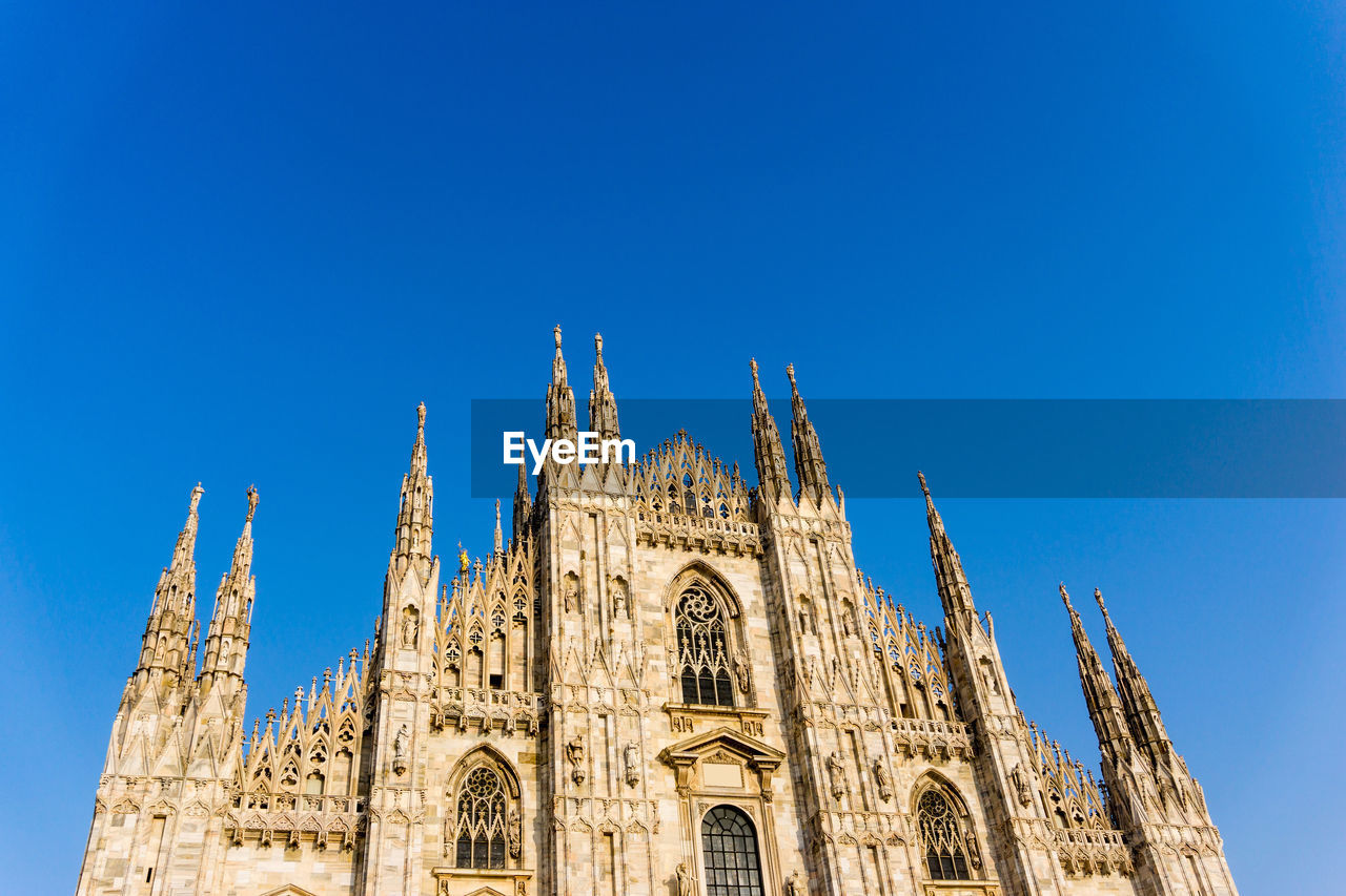 Low angle view of milan cathedral against clear blue sky