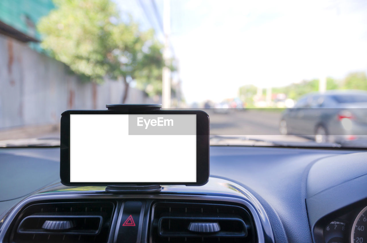 Close-up of smart phone with blank screen on car dashboard