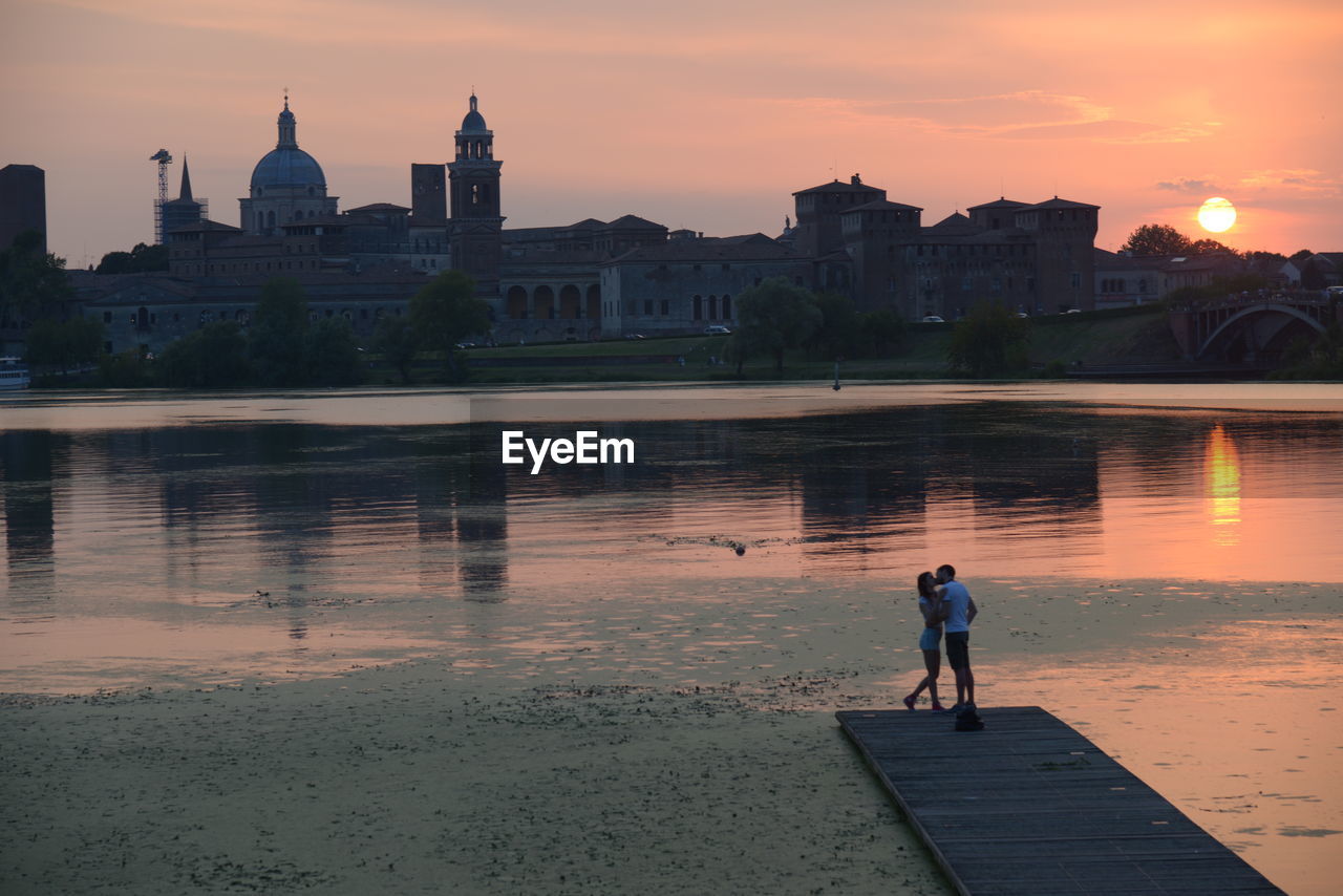 PEOPLE STANDING ON BUILDING DURING SUNSET