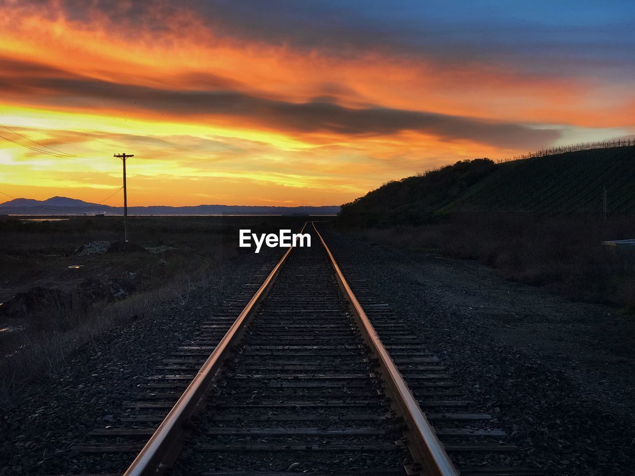 Railroad tracks against sky during sunset