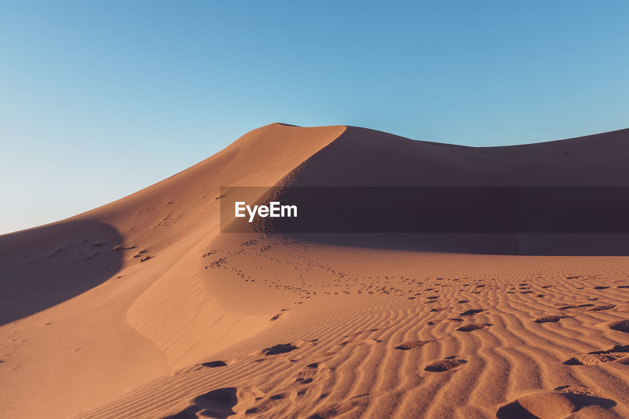 Scenic view of desert against clear blue sky