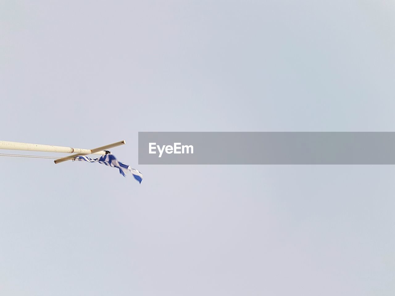 Low angle view of greek flag on ship mast against clear sky