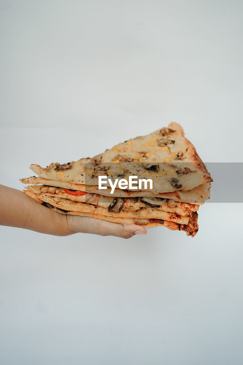 Cropped hand of person holding bread against white background