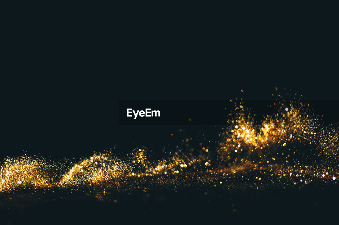 Close-up of gold glitter against black background