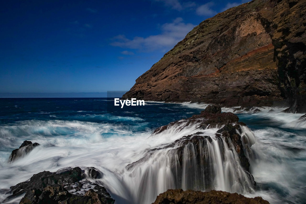 Scenic view of rocks in sea against sky