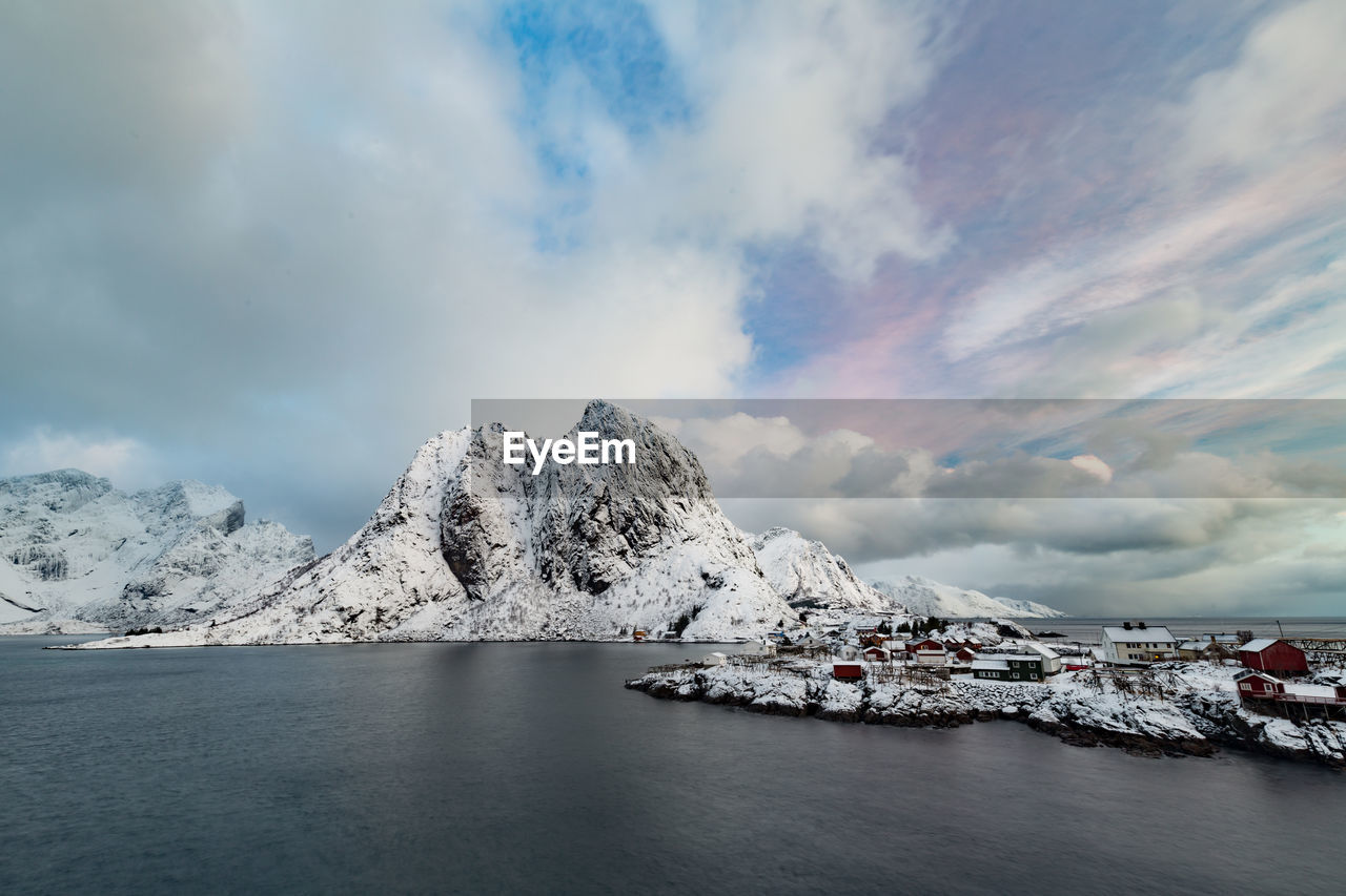 Scenic view of snowcapped mountains by sea against cloud sky