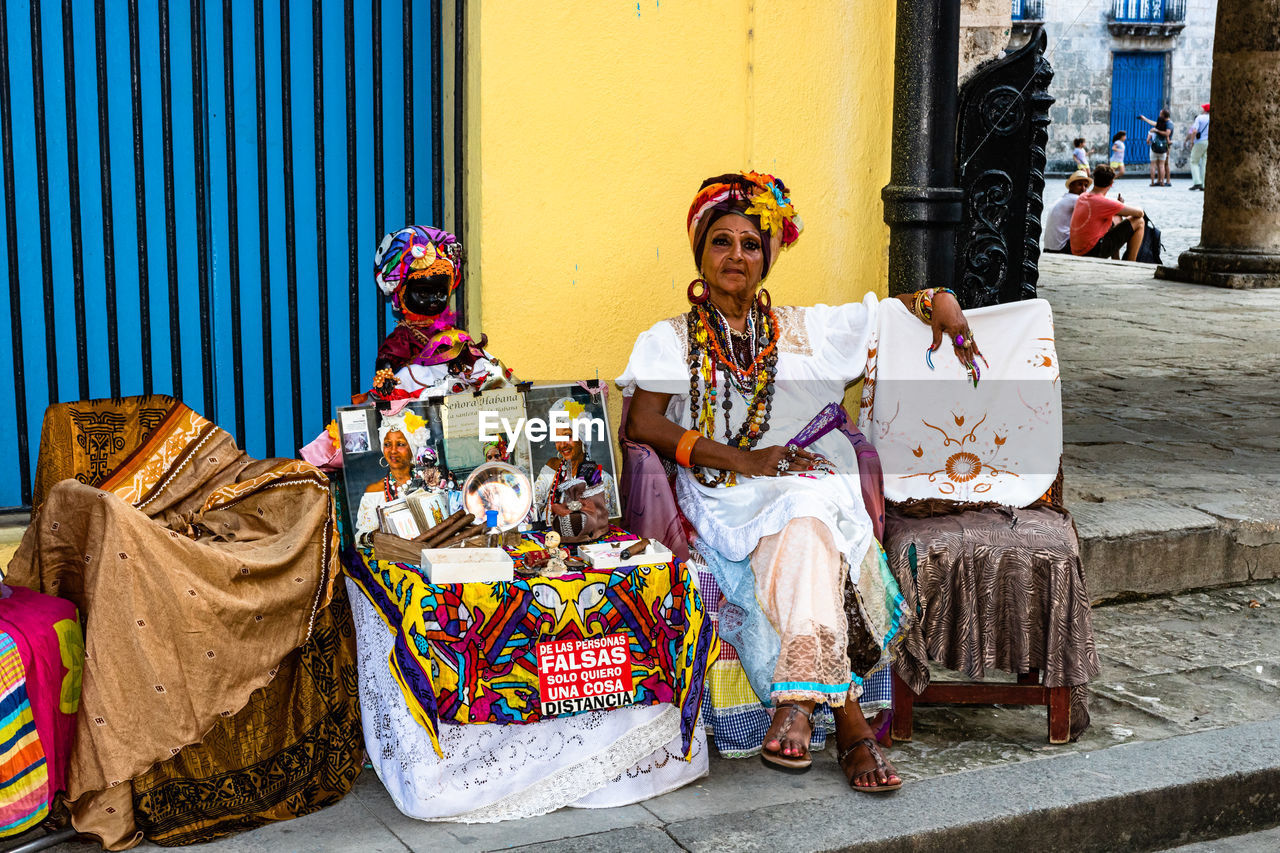 PORTRAIT OF WOMAN SITTING ON STREET WITH ARMS