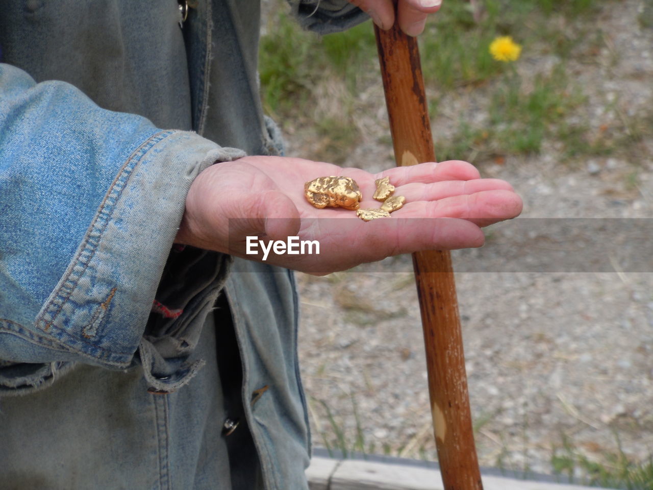 Midsection of man holding gold nugget outdoors