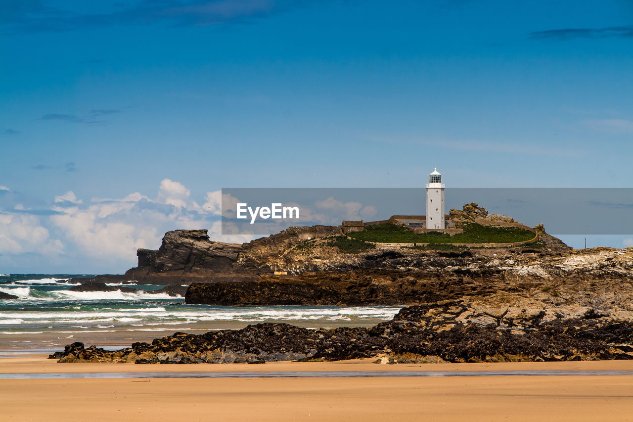 LIGHTHOUSE ON SHORE AGAINST SKY