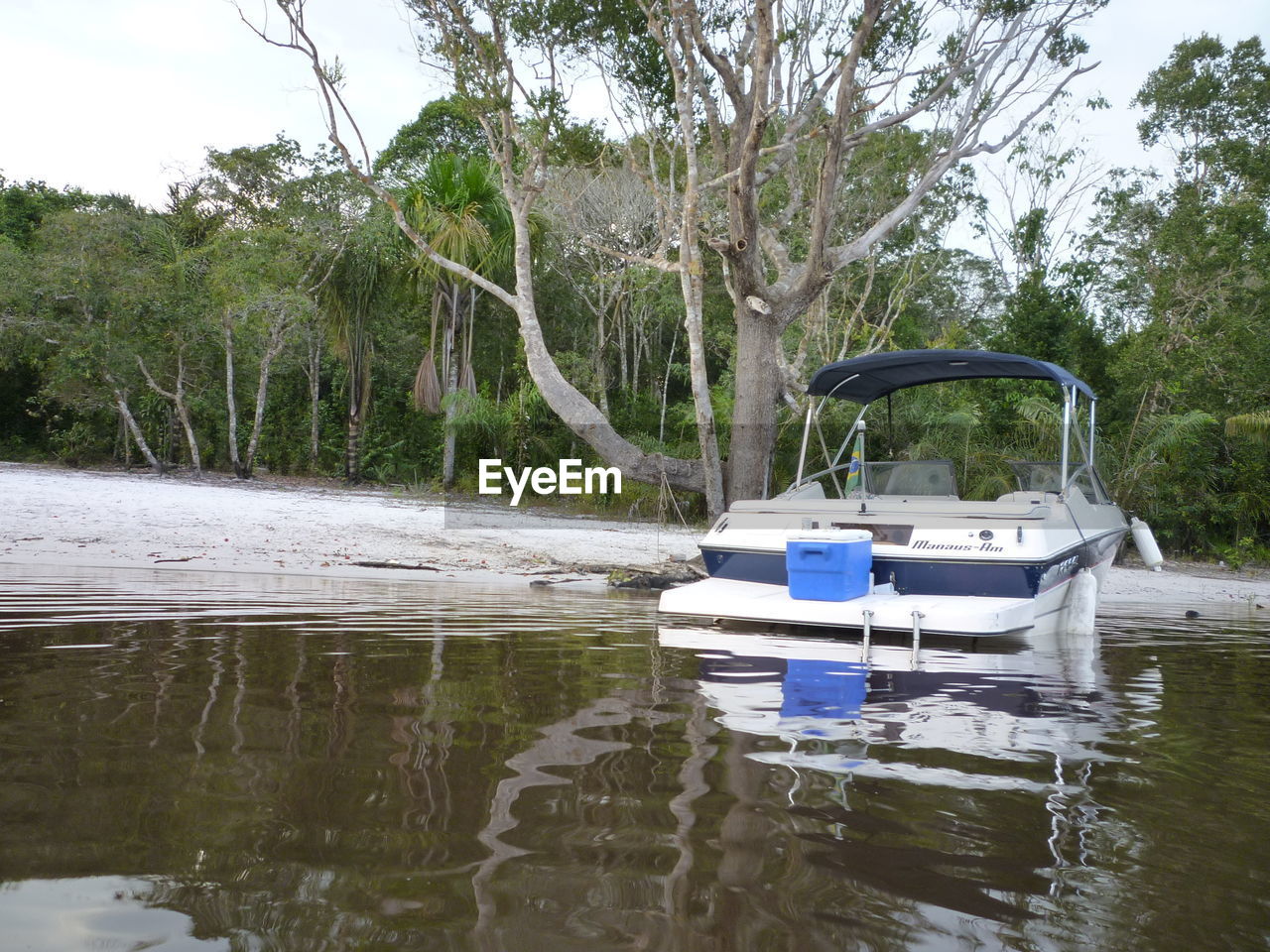 Boat in lake by trees against sky