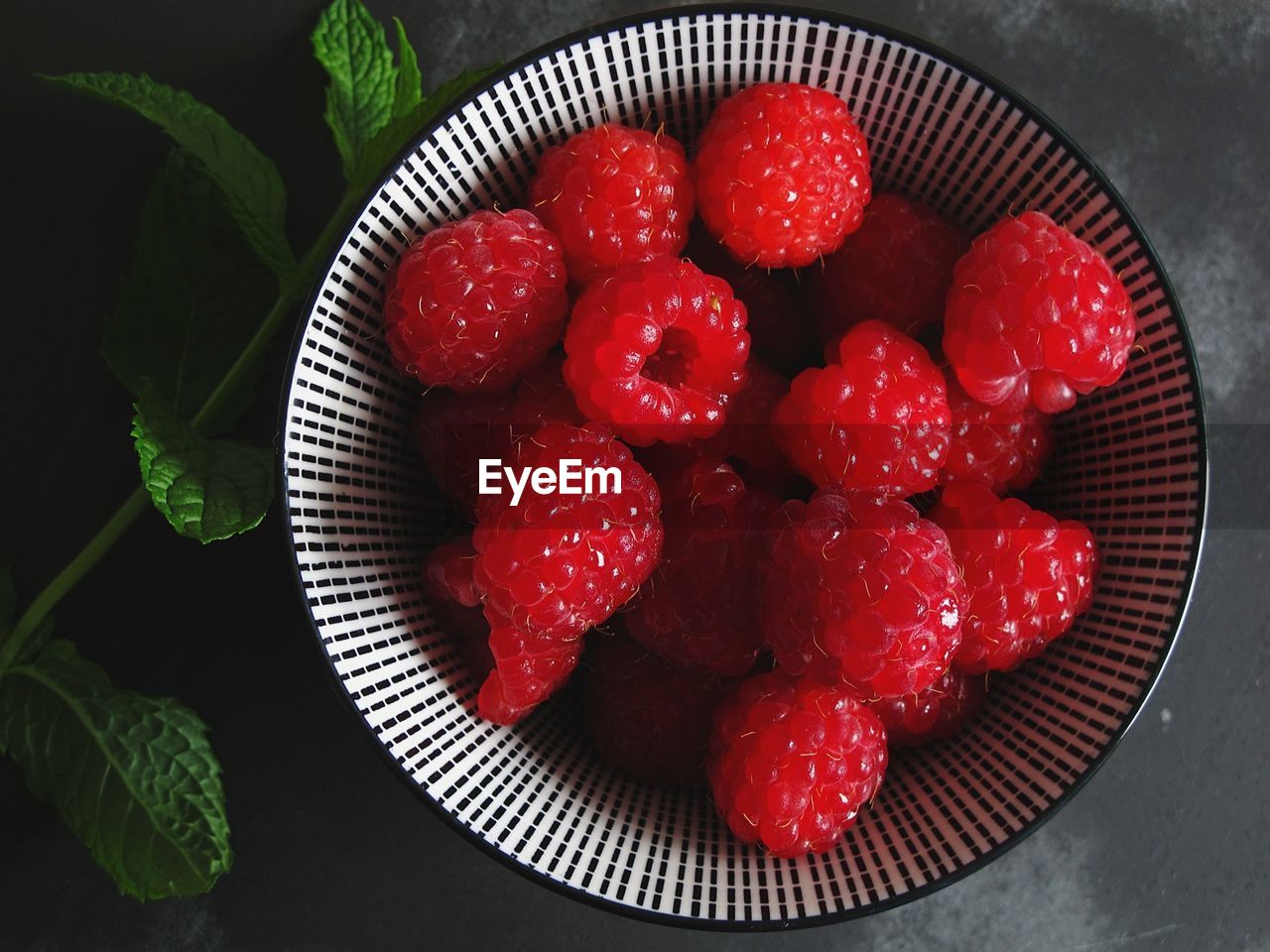 Directly above shot of raspberries in bowl and mint on table