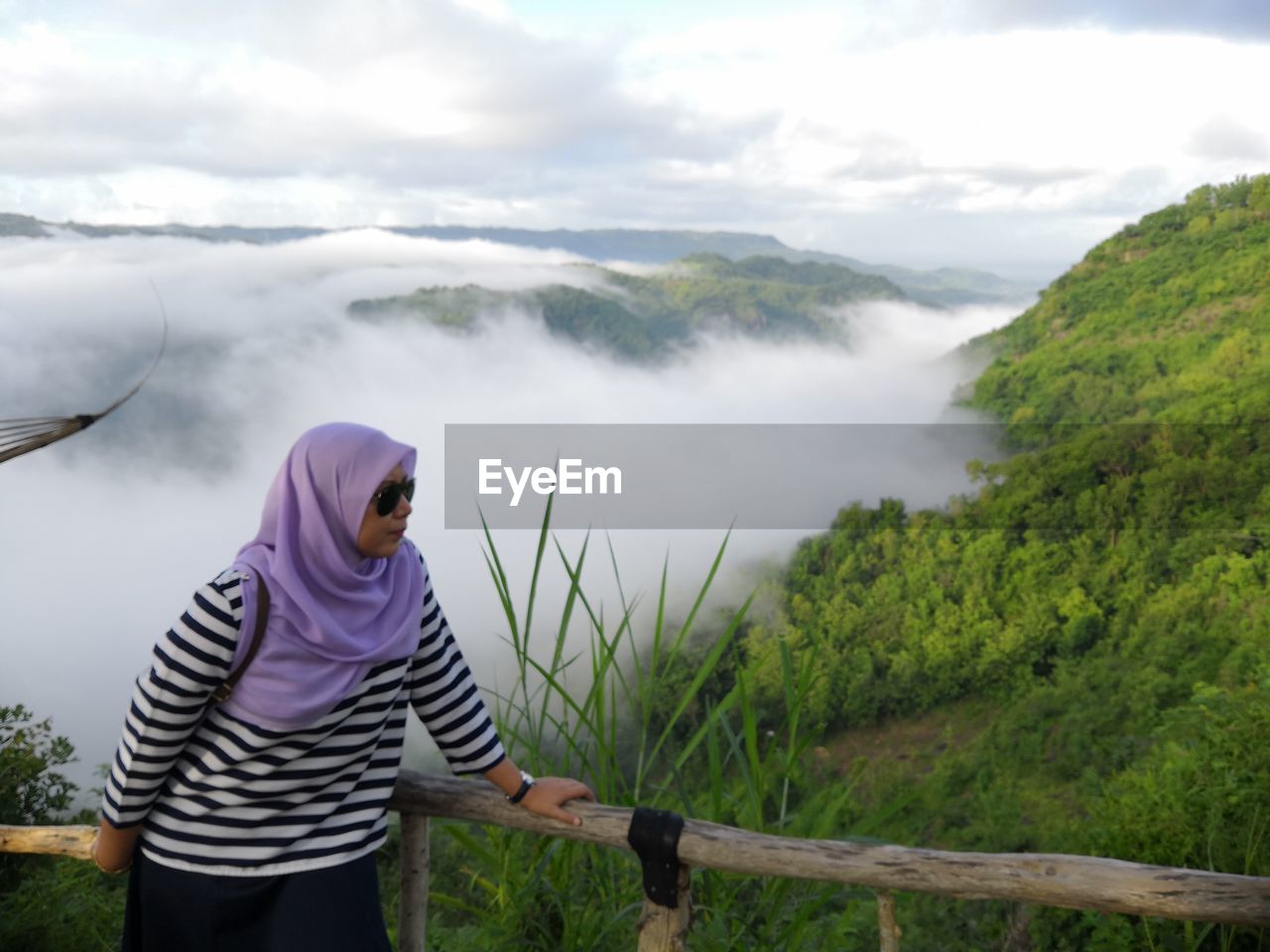 WOMAN STANDING ON MOUNTAIN AGAINST SKY