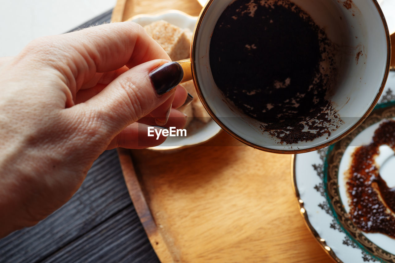 HIGH ANGLE VIEW OF HAND HOLDING COFFEE