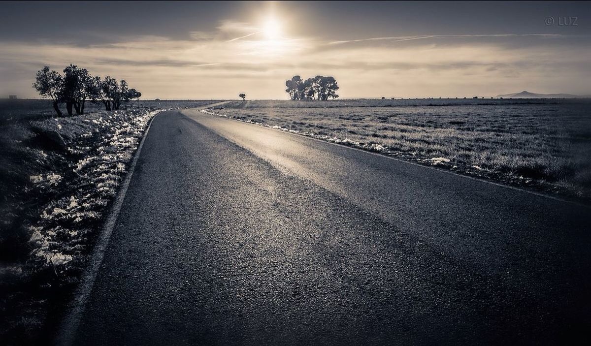 Road amidst grassy field against sky