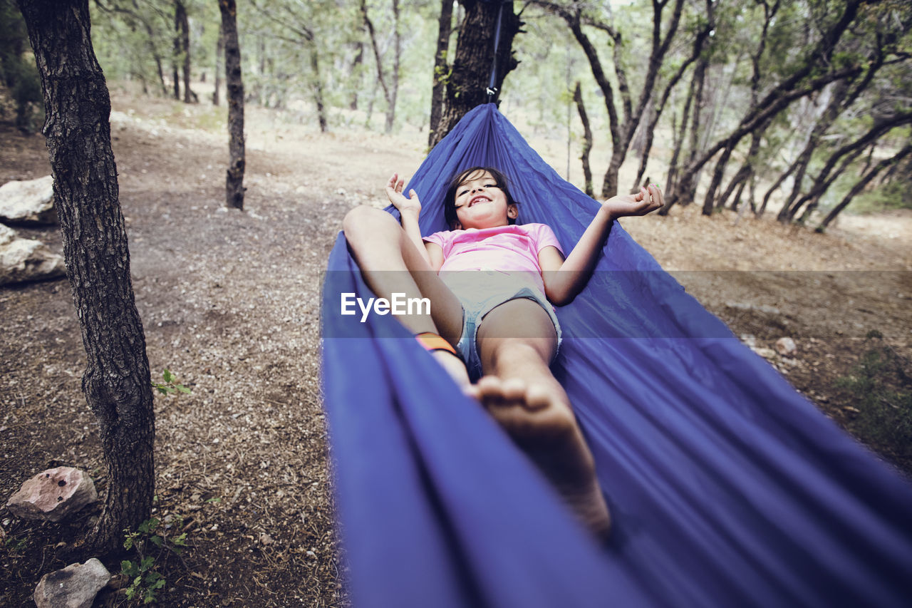 Girl lying on hammock in forest