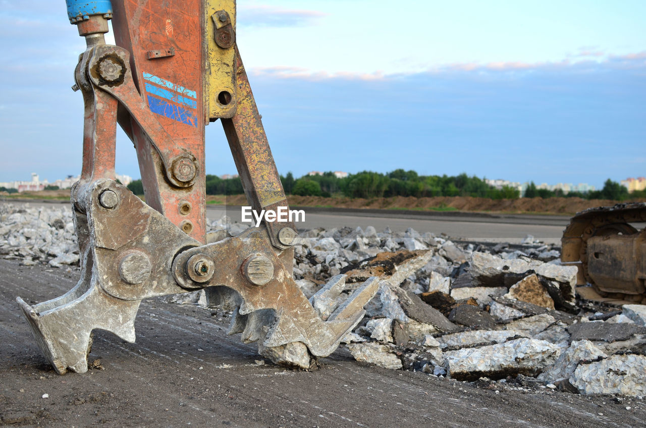 OLD RUSTY MACHINE PART ON ROAD AMIDST FIELD