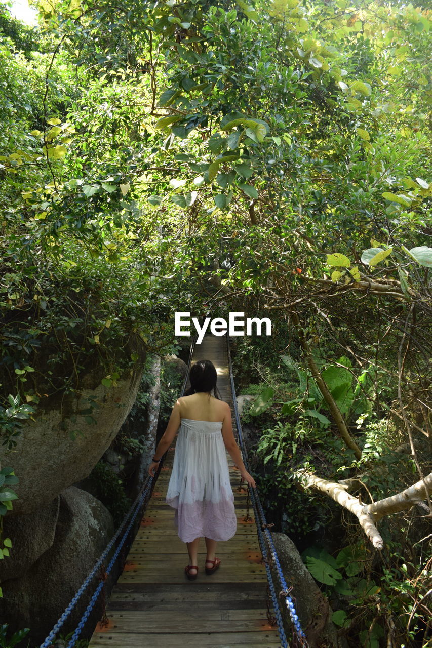 Rear view of woman walking on footbridge