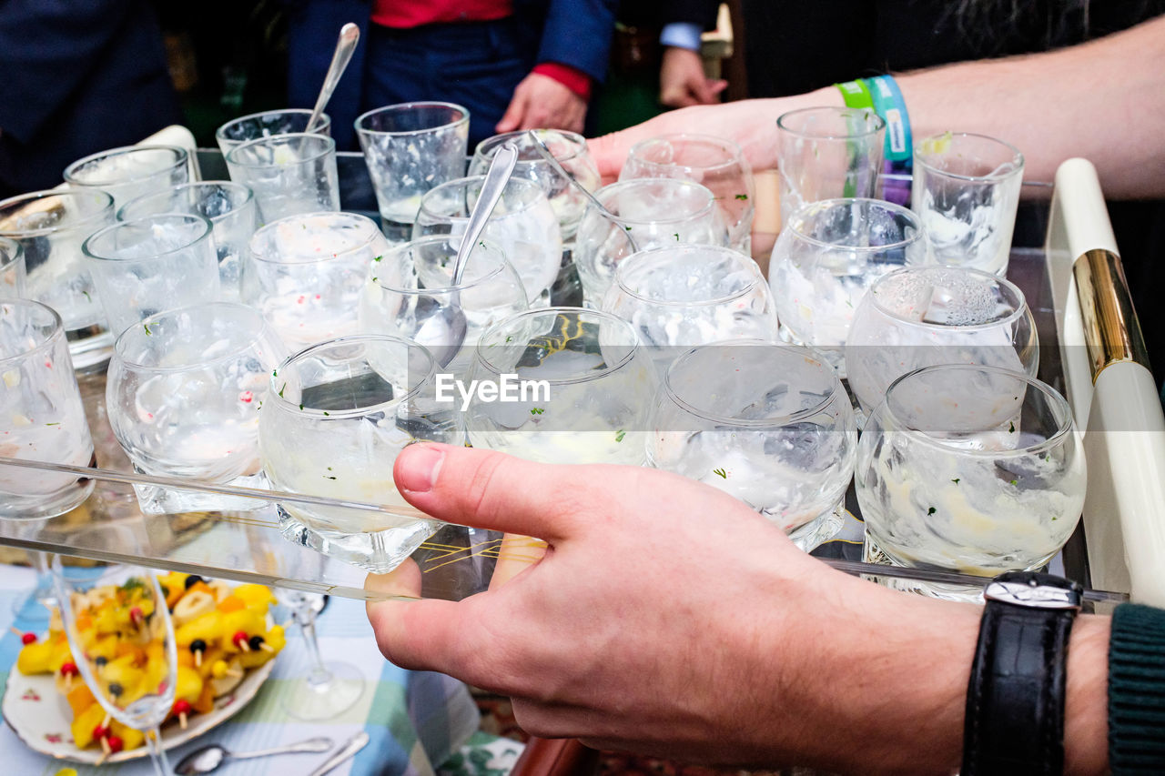 hand, glass, food and drink, drinking glass, refreshment, drink, celebration, household equipment, food, adult, alcohol, event, table, holding, meal, group of people, men, wine glass, women, party, lifestyles, business, wine, indoors, freshness, restaurant, midsection, close-up, friendship