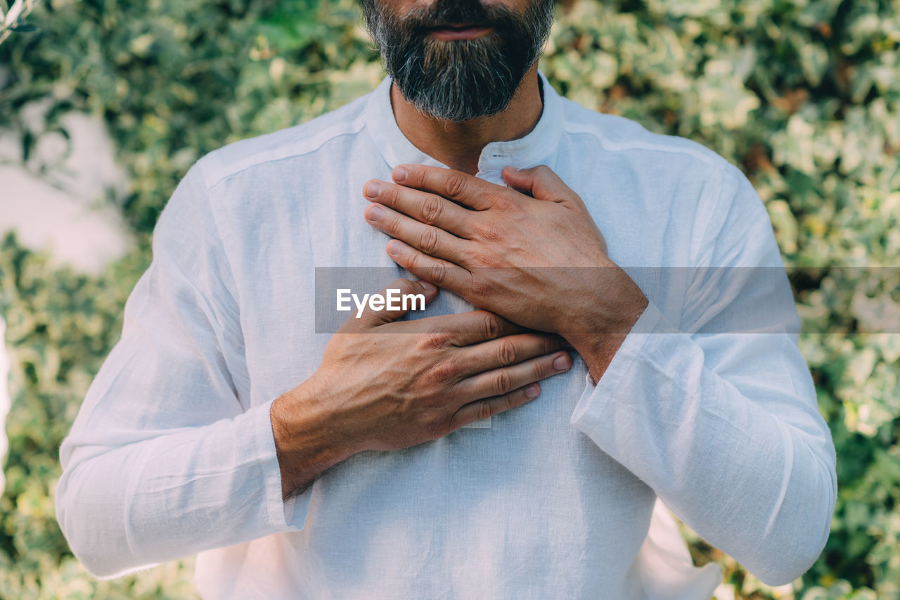 Reiki spiritual self-treatment healing session. man holding hands above the heart chakra.