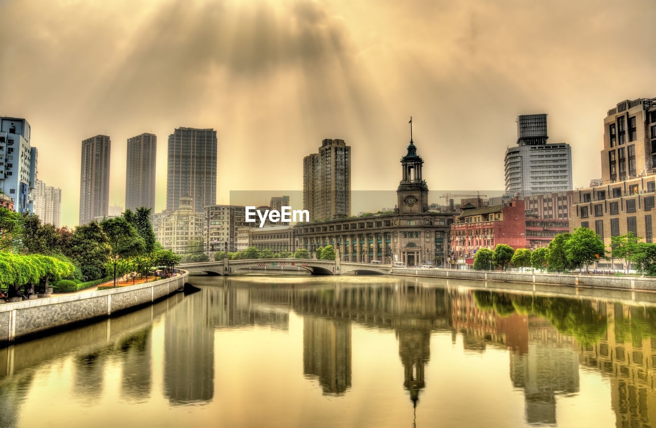 REFLECTION OF BUILDINGS IN CITY AT WATERFRONT