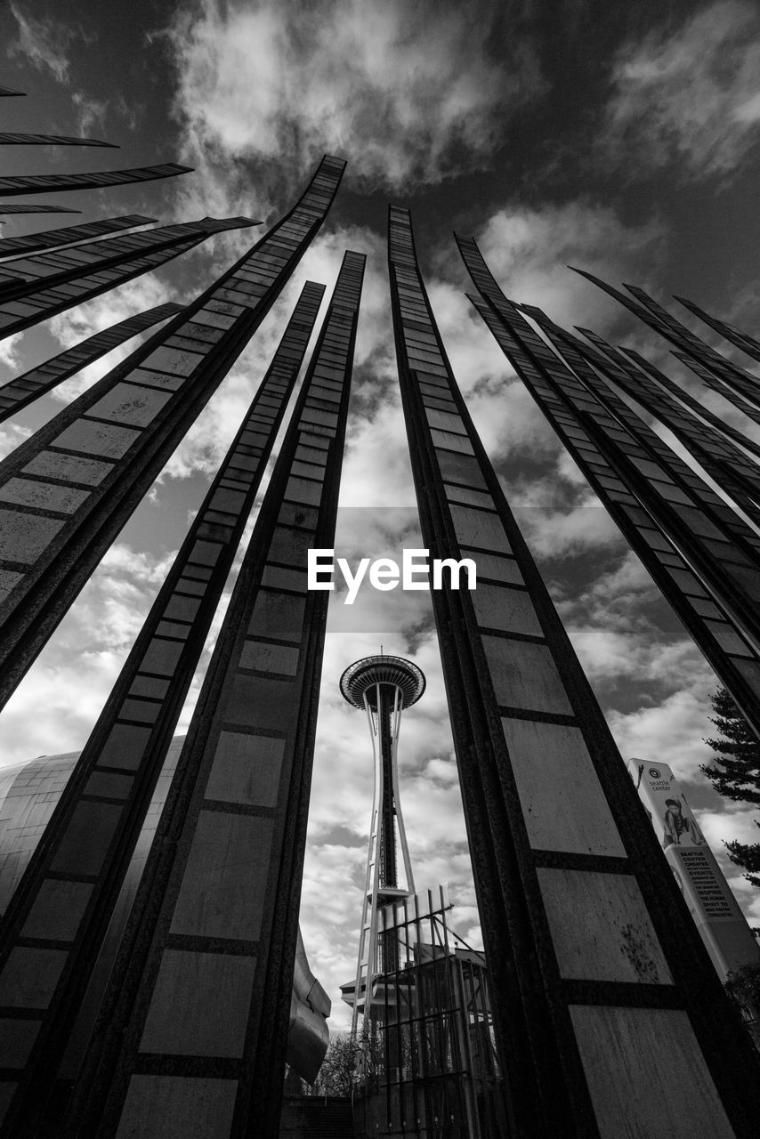 Low angle view of art installation and space needle against cloudy sky