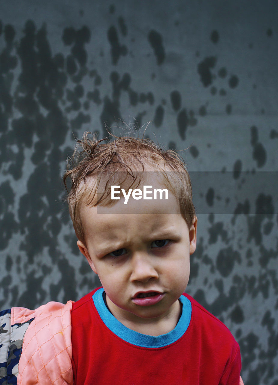 Little boy boy not happy with rain, funny face, wet child outdoors