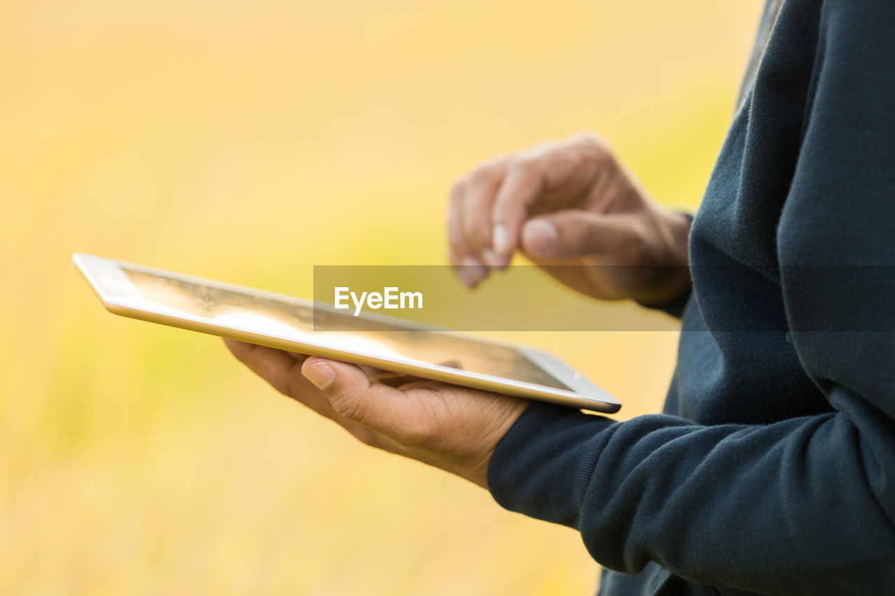 Midsection of man using digital tablet outdoors