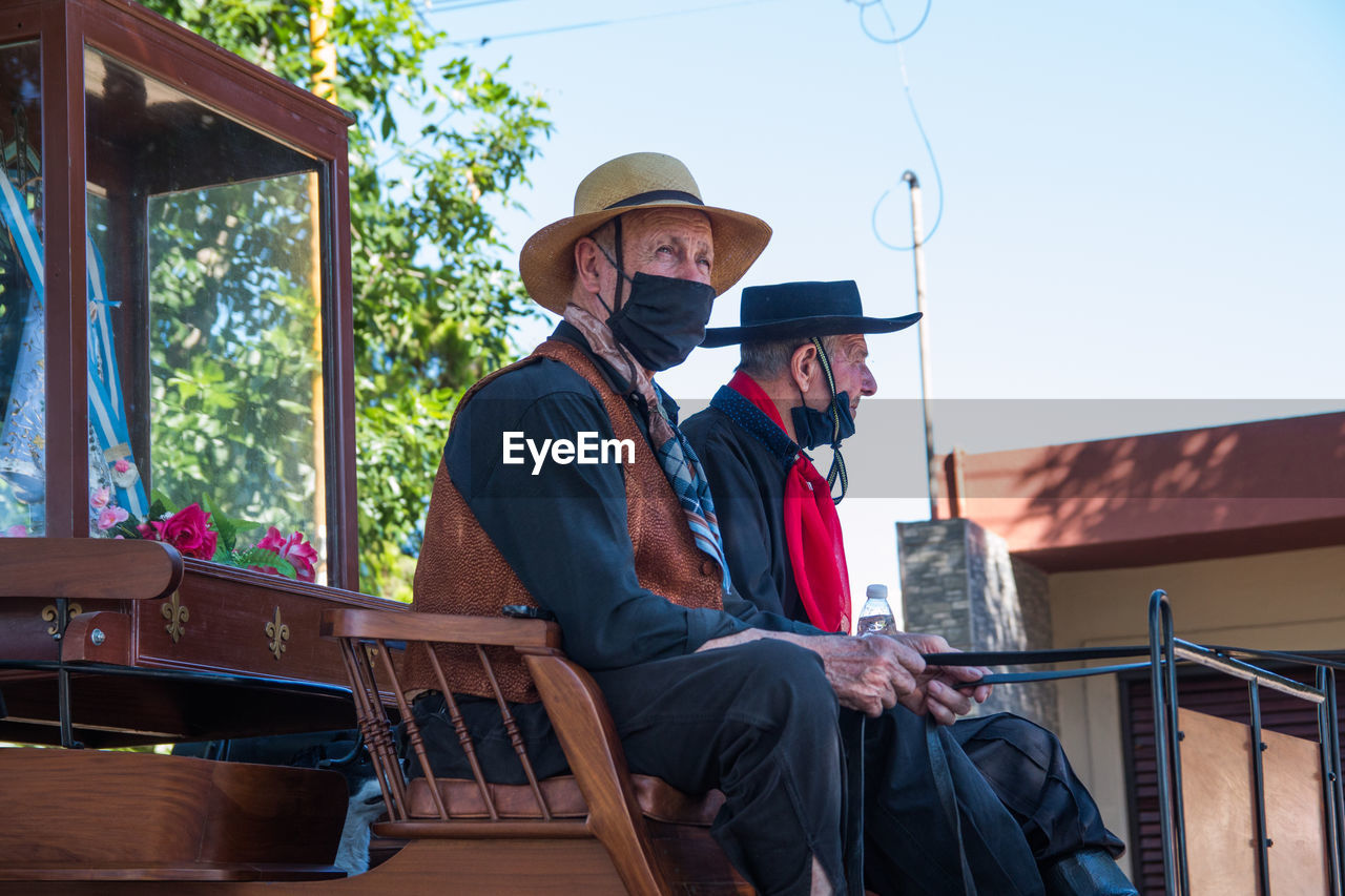 Senior adult men riding antique cart in south american festival