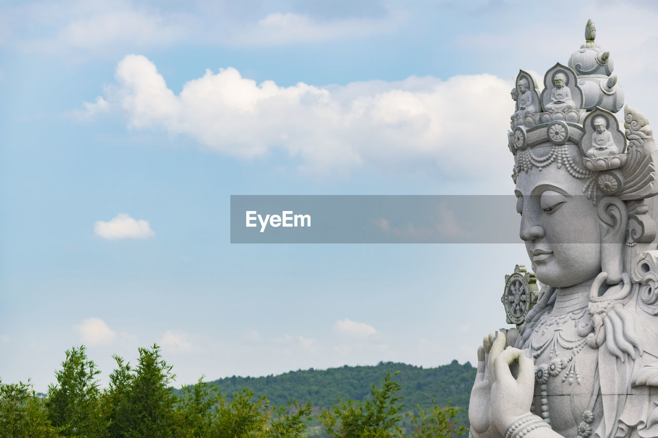 LOW ANGLE VIEW OF STATUE AGAINST SKY AND PLANTS