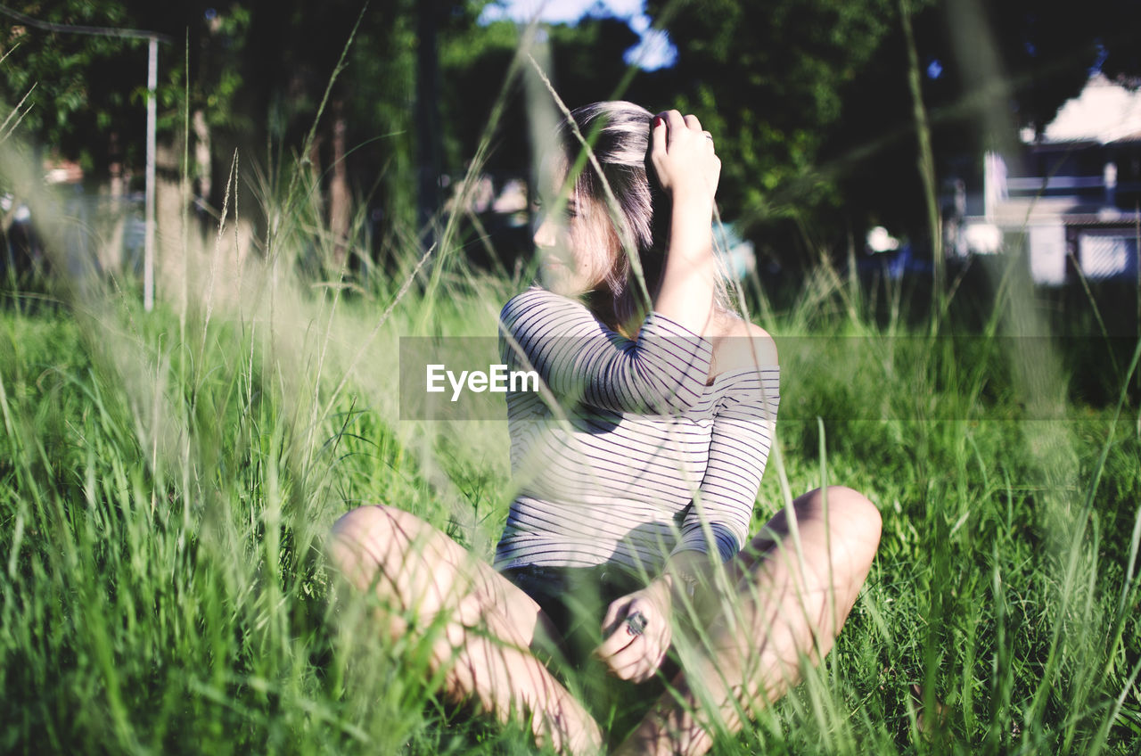 Woman looking away while sitting on grass