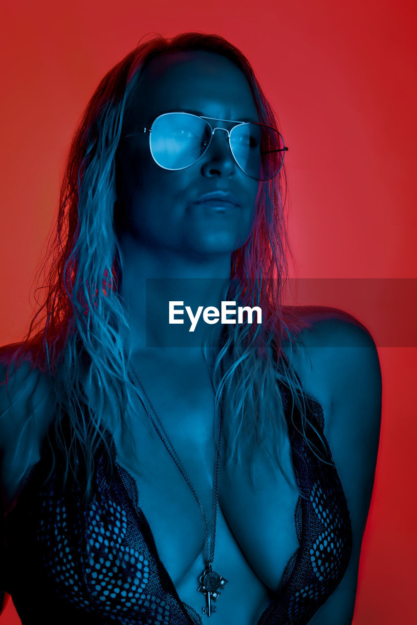 Woman wearing sunglasses against red background