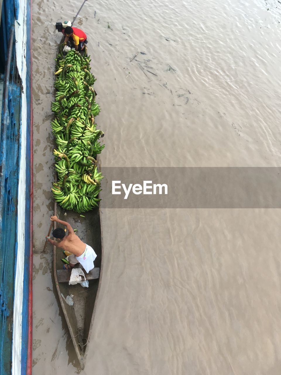 Directly above shot of man rowing canoe full on bananas on river