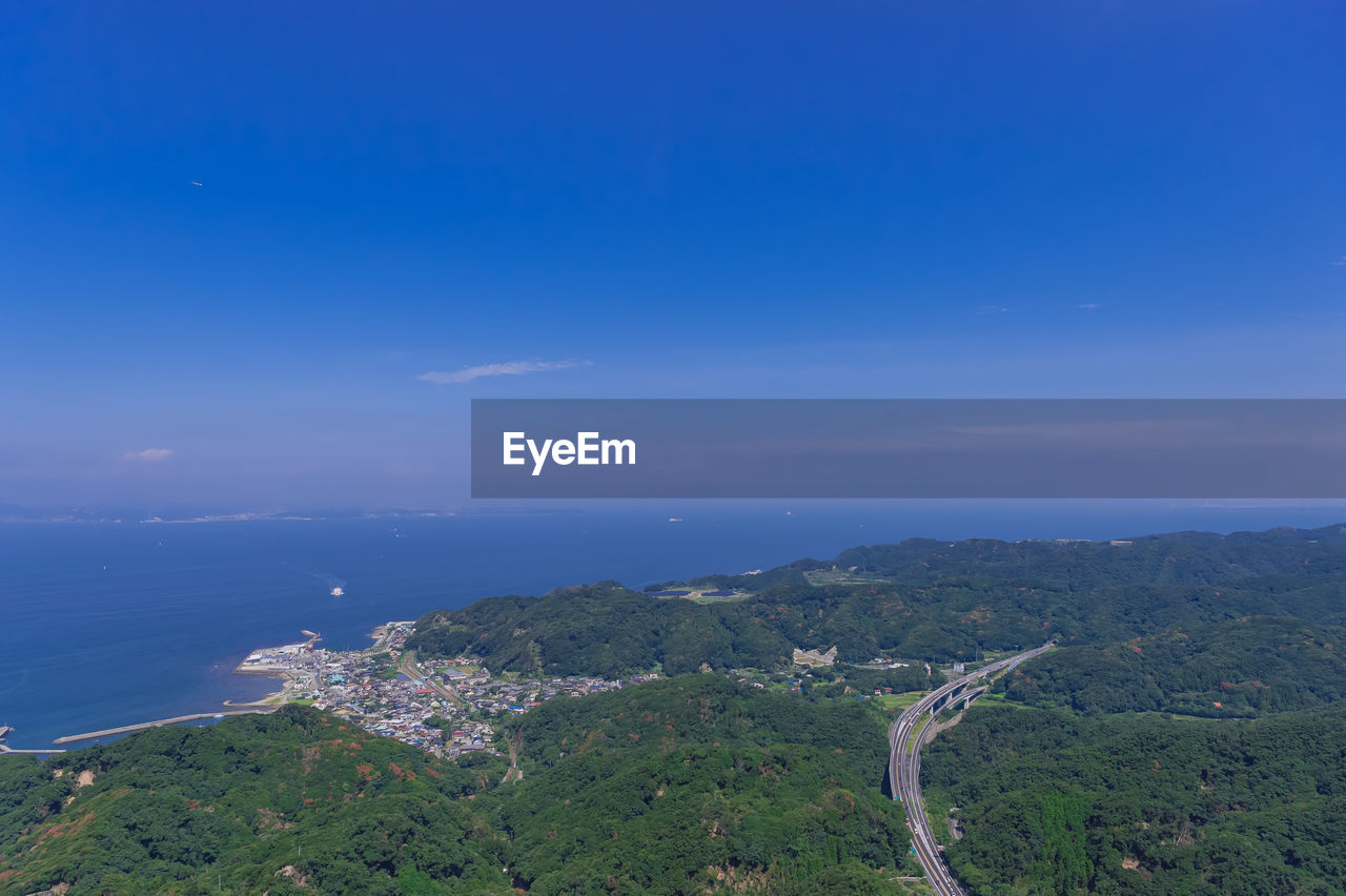 High angle view of sea and mountains against blue sky