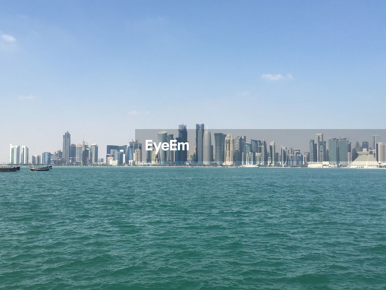 Sea by modern buildings against sky in city