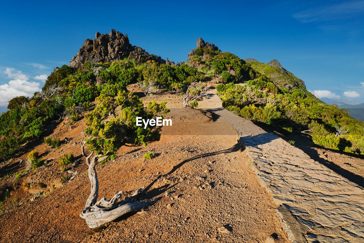 low section of man standing on rock formations against sky