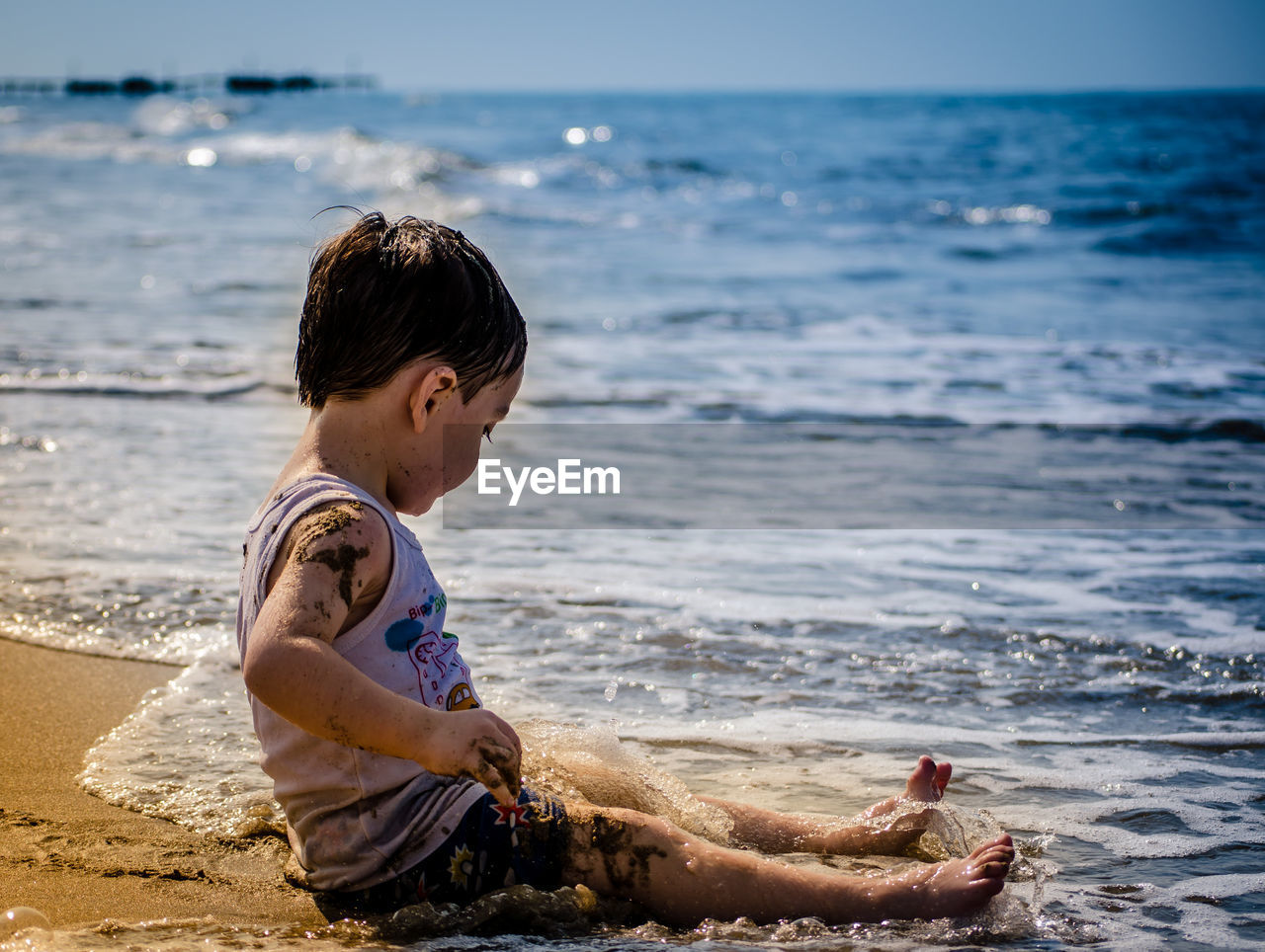 Full length of cute boy sitting at beach