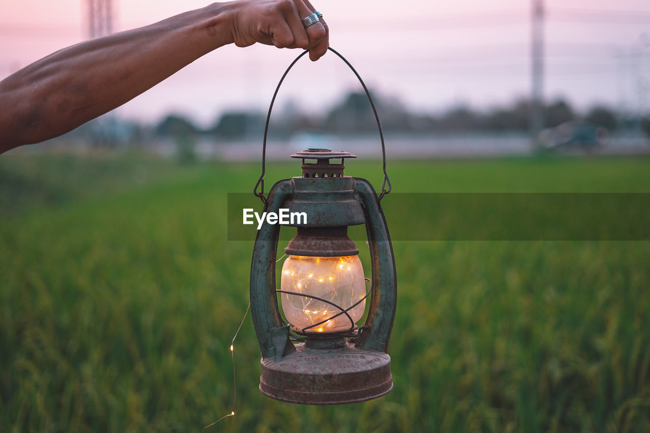 Cropped hand holding illuminated lantern