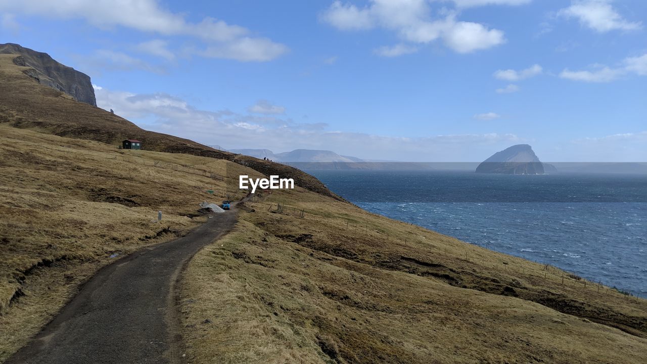 Scenic view of road by sea against sky
